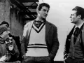 Uomini in abiti d'epoca, uno con un maglione a V, discutono animatamente. Un'iconica scena della commedia all'italiana.