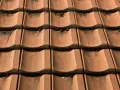 Czerwona dachówka ceramiczna, lekko porośnięta mchem. Sprawdź aktualną dachówka ceramiczna cena za m2.