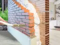 Applicazione di schiuma isolante termica in una parete di mattoni per un maggiore comfort abitativo.