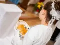 Dziewczynka w bieli trzyma koszyczek z opłatkiem. Zastanawiasz się, ile daje chrzestny na komunię?