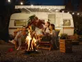 Freunde genießen einen gemütlichen Abend bei Lagerfeuer und Gitarrenmusik während ihres Campingurlaubs in Deutschland.