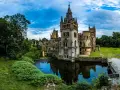 Zamek Kopyce, otoczony fosą i bujną zielenią, majestatycznie odbija się w spokojnej tafli wody.
