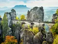 Most Bastei, skalne miasto w Saksonii, z kamiennym mostem łączącym skalne iglice. Jesienne liście dodają koloru krajobrazowi.
