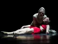 Una escena dramática de "Romeo y Julieta resumen corto": una mujer con capucha grita sobre otra, vestida de rojo, que yace en el suelo.
