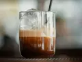 Orzeźwiające freddo espresso z lodem i pianką w szklance, gotowe do wypicia.