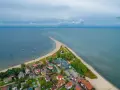 Malownicza miejscowość nad morzem, z domkami i plażą, wcinająca się w spokojne wody.