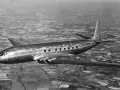 Pierwszy samolot pasażerski, lśniący de Havilland Comet, przelatuje nad patchworkiem pól.