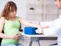 Lekarz pobiera krew od ciężarnej kobiety, aby sprawdzić poziom glukozy w ciąży.