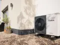 Unità esterna Vaillant per raffrescamento con termosifoni, posizionata su ghiaia vicino a una casa moderna.