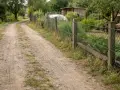 Droga wewnętrzna biegnie wzdłuż siatkowego ogrodzenia, wyznaczając minimalną odległość od granicy działki.