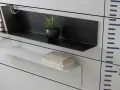 Moderna soluzione per arredare una parete con mensole: una nera con libri e pianta, una bianca con libri.