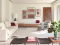 Una composición de cuadros en la pared, con arte abstracto y tipografía, decora este salón moderno junto a un sofá blanco y una butaca gris.