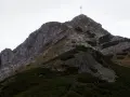 Wspinaczka na Giewont. Grupa turystów pokonuje skaliste zbocze, gdzie w trudniejszych miejscach pomagają łańcuchy.