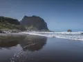 Dziecko bawi się na czarnej plaży Madera, w tle widać skaliste klify i ocean.