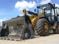 Żółta ładowarka stoi na piasku. Zastanawiasz się, ile zarabia operator koparki?