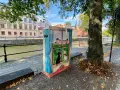 En målad låda med två katter som tittar ut genom ett fönster på ett slott. Konstnären har valt att måla tunt för att ge en drömsk känsla.