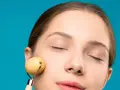 Mujer con ojos cerrados disfrutando de un masaje facial antienvejecimiento y drenaje con rodillo de jade.