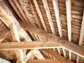 Vue rapprochée d'une charpente ancienne en bois, témoignant d'un savoir-faire artisanal. Un futur projet de traiter charpente pour la préserver.