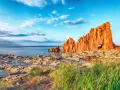 Scogliere rosse a picco sul mare blu, con un arco naturale, vicino ad Arbatax centro storico.