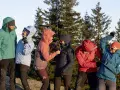 Sechs Personen in bunten Hardshelljacken stehen vor Bäumen. Eine Hardshelljacke schützt vor Wind und Wetter.