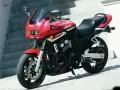 Czerwony motocykl Yamaha FZ6 z czarnym siedzeniem i owiewką, zaparkowany na zewnątrz.