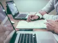 Dwie osoby pracują nad dokumentem, analizując dane. To może być przygotowanie do imprezy firmowej, gdzie różnica między zaproszeniem formalnym a nieformalnym na imprezę firmową jest kluczowa.