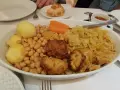Un plato generoso de cocido madrileño con garbanzos, patatas, zanahoria, repollo y trozos de carne frita.