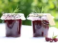 Zwei Gläser Jostabeere-Marmelade, liebevoll mit Rosmarin und kariertem Band verziert. Perfekt für die Jostabeere Verwendung auf Brot.