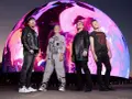 U2 w nowej płycie. Czterech członków zespołu stoi przed gigantycznym, kolorowym ekranem.
