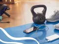 Gotowy na trening cardio? Kettlebell, gumy oporowe, rolka do ćwiczeń i telefon z powerbankiem czekają na matę.