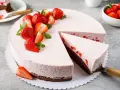 Ein köstlicher Erdbeer Schmand Kuchen in Springform, dekoriert mit frischen Erdbeeren und Minze. Ein Stück wurde bereits entnommen.