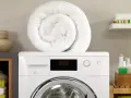 Piumone bianco arrotolato sopra una lavatrice. Pronto per essere lavato in lavatrice a 40 gradi per un bucato fresco e pulito.
