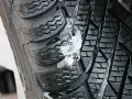 Gomme invernali con neve e ghiaccio incastrati nel battistrada. Le gomme screpolate battistrada mostrano segni di usura, ma ancora funzionali.