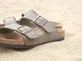 Sandali Birkenstock grigi sulla sabbia. Scopri come si lavano le Birkenstock per mantenerle perfette.