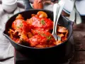 Pollo alla Marengo succulento in padella con funghi e pomodoro, guarnito con timo fresco.