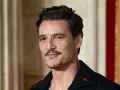 Pedro Pascal con cortes de pelo hombre corto por los lados y largo arriba, luciendo un pin de cerilla en su solapa.