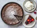 En saftig snabb kladdkaka i form, pudrad med florsocker. En bit serveras med bär och vispgrädde.