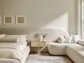 Dormitorio con decoración minimalista, cama baja, sofá curvo y arte abstracto en tonos tierra.