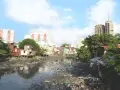 Un río lleno de basura y aguas residuales, rodeado de casas precarias y edificios modernos, ilustra los graves tipos de contaminación que afectan a esta comunidad.