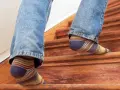 Füße in bunten Socken steigen eine Holztreppe hinauf, die auf eine Renovierung wartet.