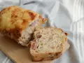Chleb pasterski z serem i wędliną, pokrojony na desce, z widocznym wnętrzem pełnym kawałków mięsa.