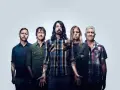 Les membres de Foo Fighters posent ensemble, cinq hommes aux regards intenses, prêts à enflammer la scène.