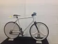 A sleek, white 3d printed bike with unique disc and tri-spoke wheels. Yellow sunglasses rest on the seat.