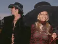Pamela Anderson i Tommy Lee w stylizacjach z epoki. Ona w wielkim kapeluszu i wzorzystej sukience, on w kowbojskim kapeluszu i futrzanej kurtce.