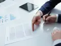 Biznesmen wskazuje palcem na dokument "CONTRACT", przygotowując się do podpisania umowy b2b.