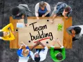 Un groupe diversifié autour d'une table discute de "team building". Ils collaborent, partageant des idées pour renforcer leur unité.