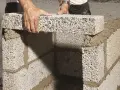 Byggare lägger mura lecablock på betongplatta. Murbruket syns mellan blocken.