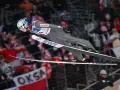 Skoki narciarskie dzisiaj: polski skoczek w locie, tłum kibiców na trybunach.