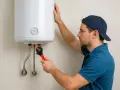 Técnico realizando la instalacion termo electrico de un calentador de agua con una llave inglesa.