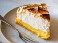 Rebanada de lemon pie con merengue dorado y relleno cremoso, lista para ser disfrutada con un tenedor.